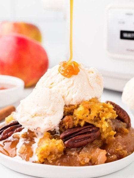 Drizzling slated caramel on a slice of a Crockpot Apple Dump Cake.