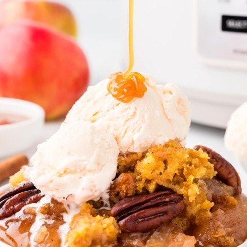 Drizzling slated caramel on a slice of a Crockpot Apple Dump Cake.