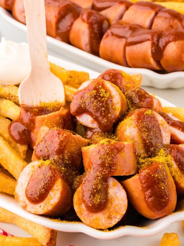German Currywurst served with French fries in a white bowl.