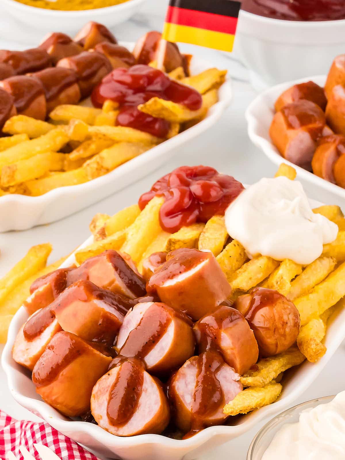 A bowl of Currywurst and French Fries topped with ketchup and mayoannaise.