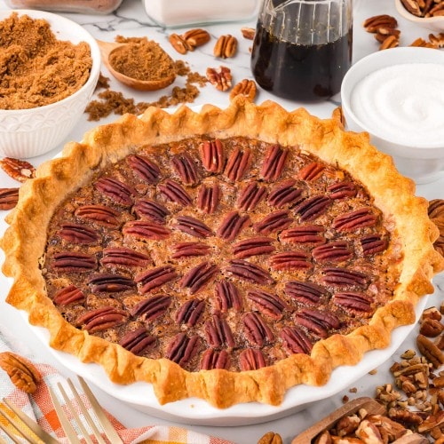 A homemade Pecan Pie in a white baking dish decorate with pecans.