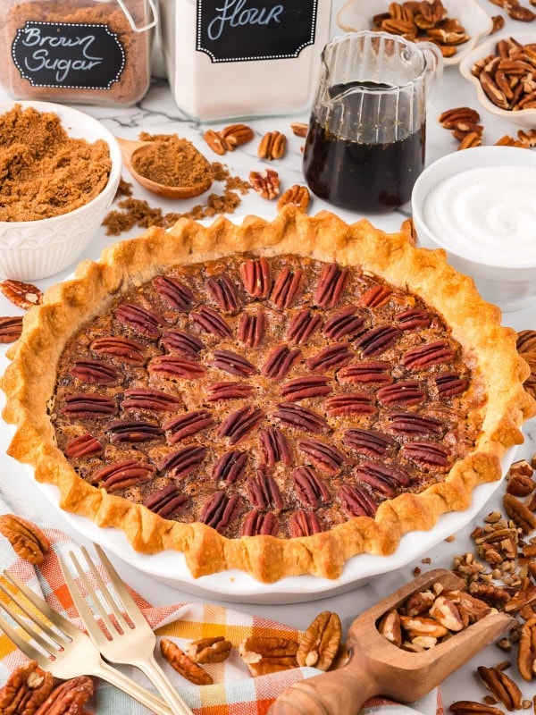 A homemade Pecan Pie in a white baking dish decorate with pecans.