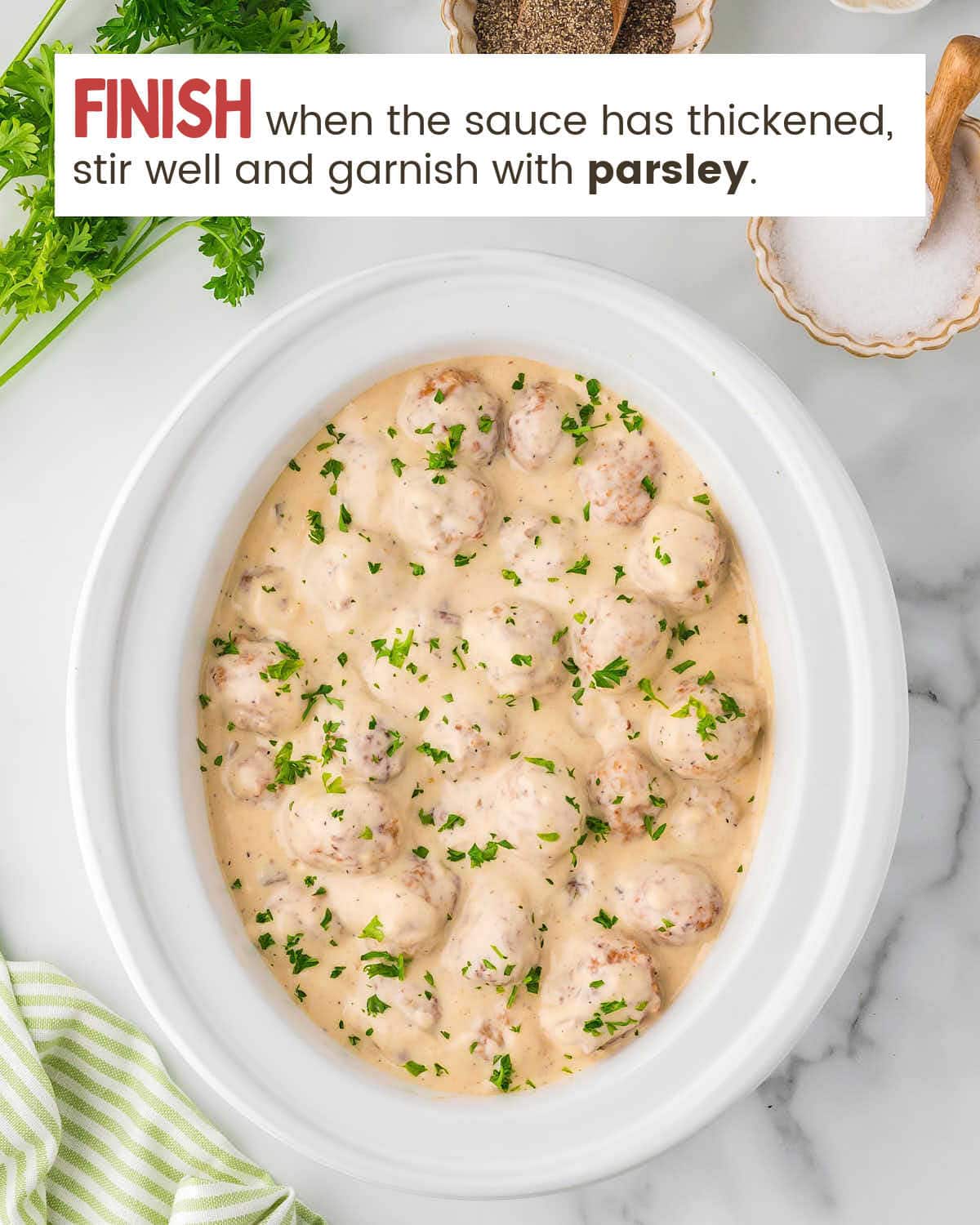 Cooked Swedish Meatballs in a slower garnished with fresh parsley.