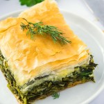 A slice of Spanakopita on a white plate.