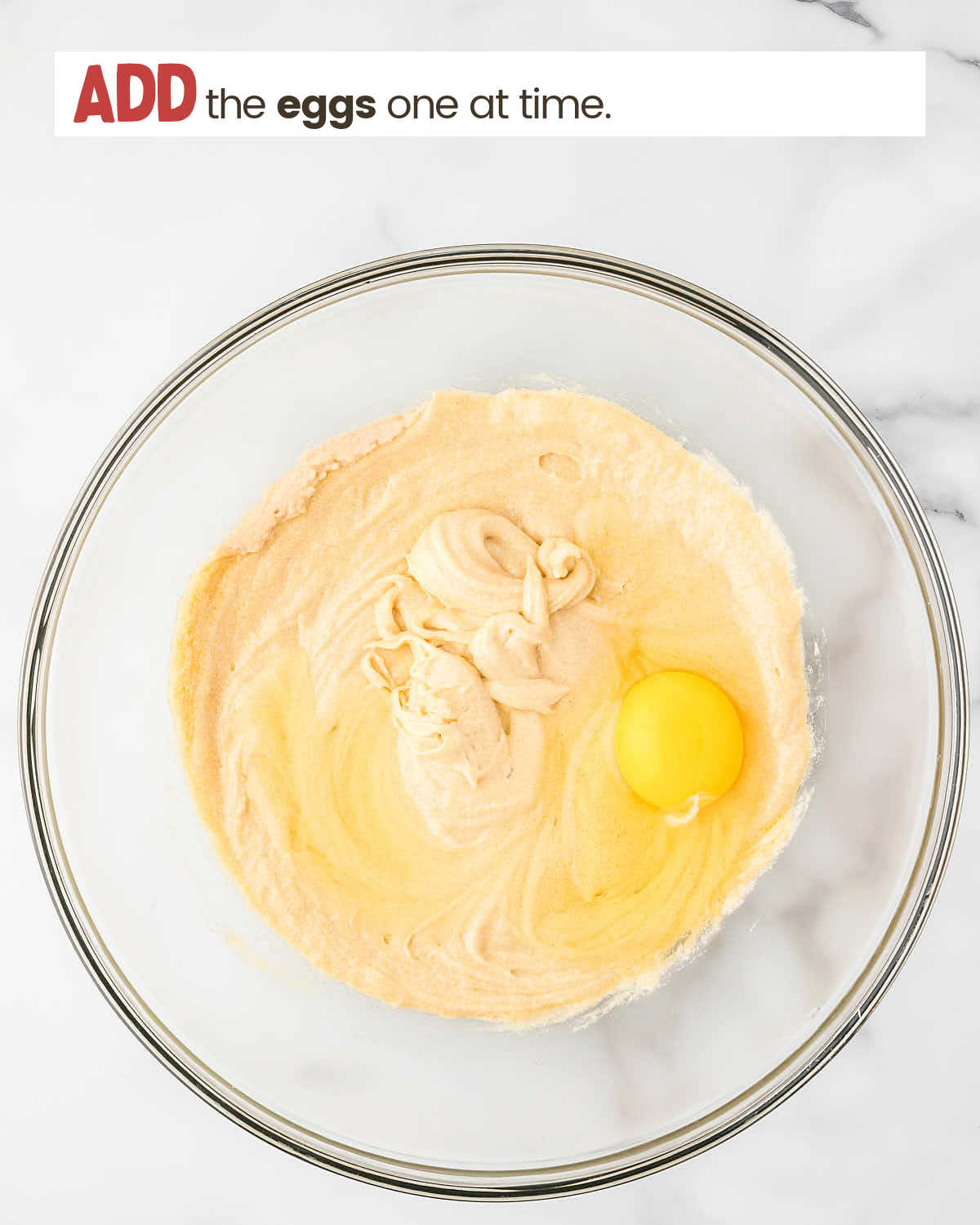 Cookie batter in a bowl with raw egg to be mixed in.