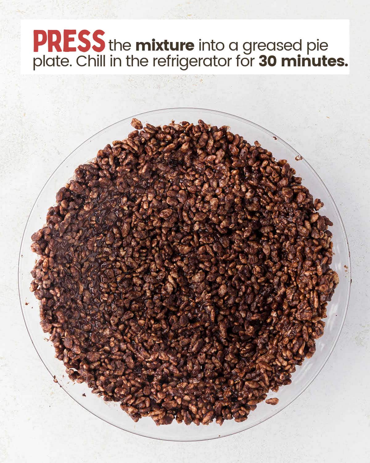 Rice crispy cereal mixed with melted chocolate in a pie plate.