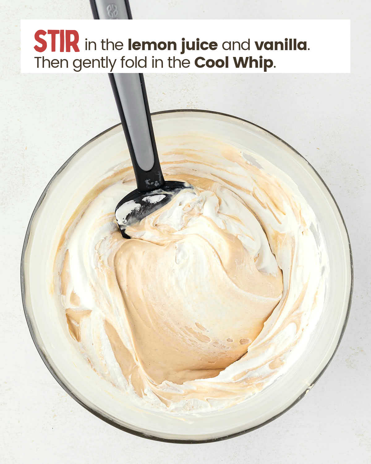 A spatula in a bowl with a whipped topping and peanut butter mixture.