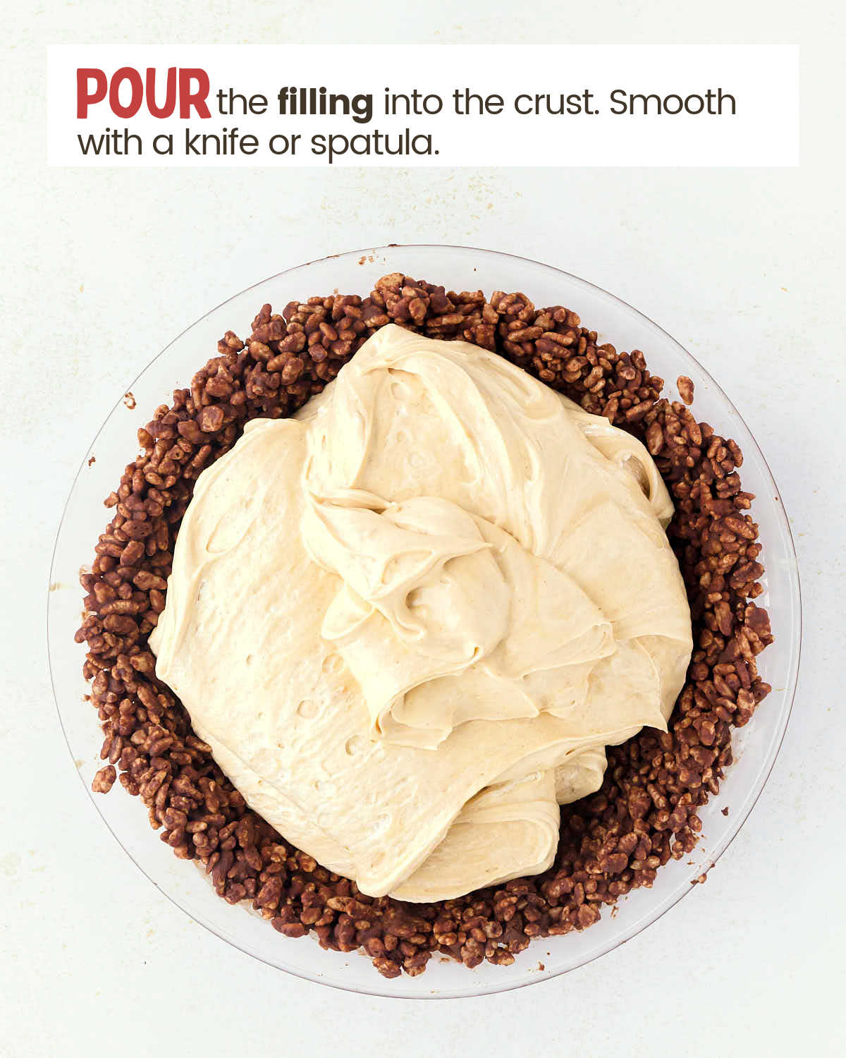 Peanut butter mixture on top of a chocolate rice crispy cereal mixture in a pie plate.