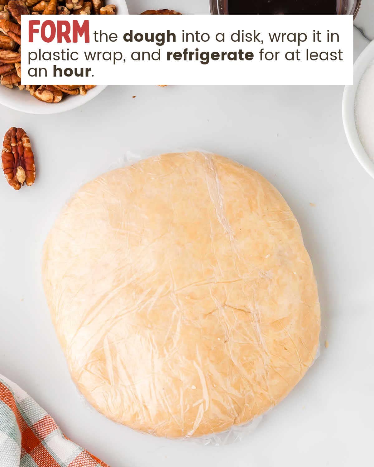 Pie crust dough ball wrapped in plastic wrap.