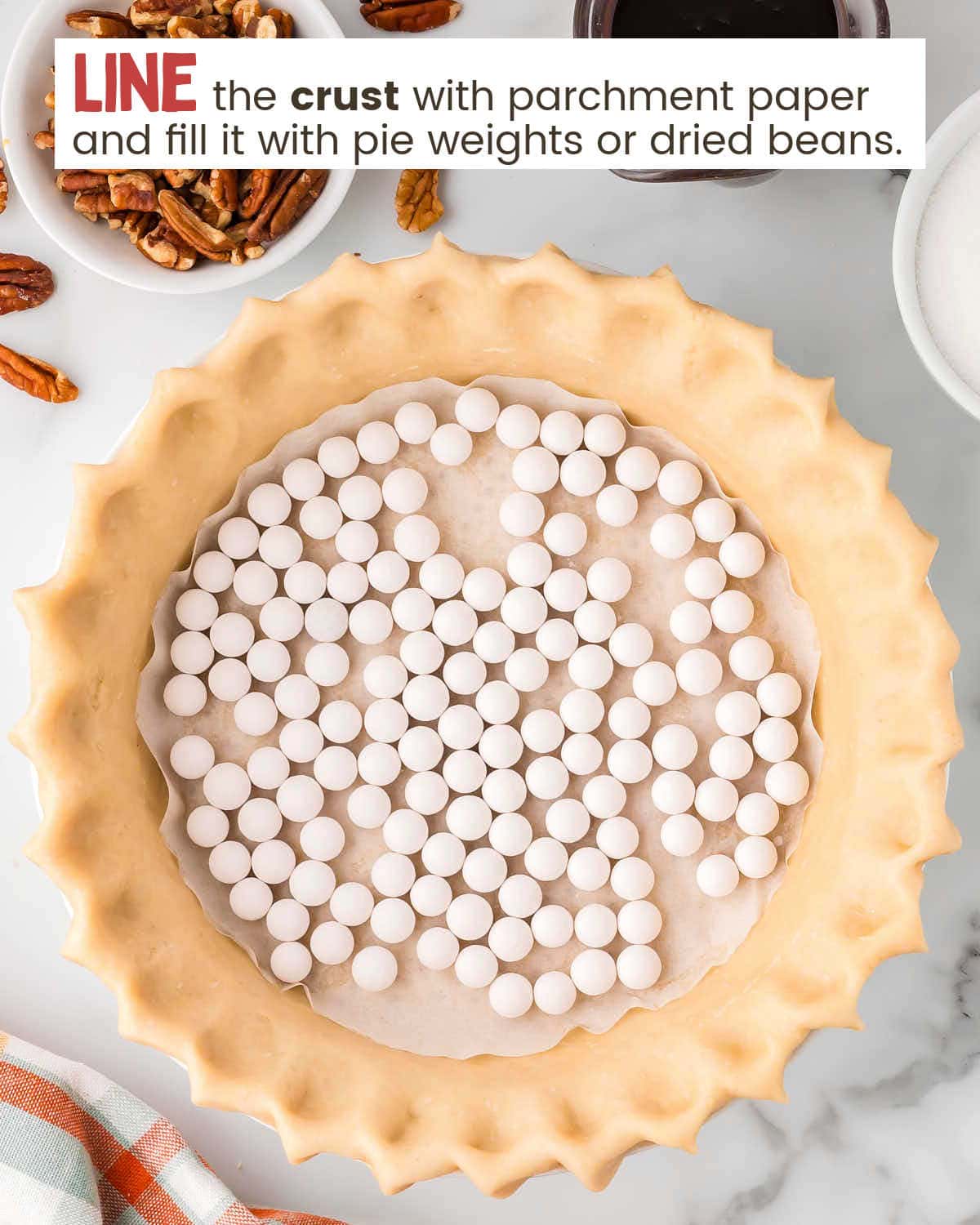 Pie crust dough in a pie plate with the center lined with parchment paper and baking weights.