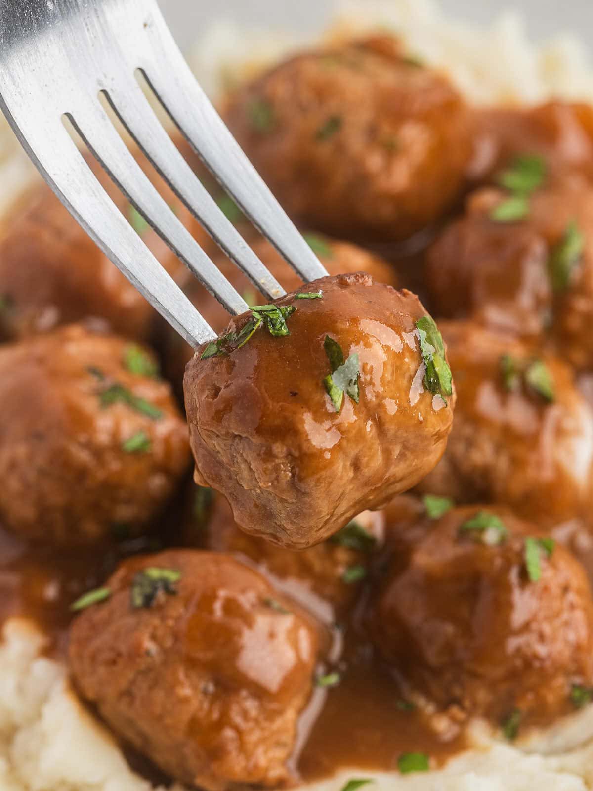 Sticking a fork into freshly cooked Meatballs smothered in gravy.