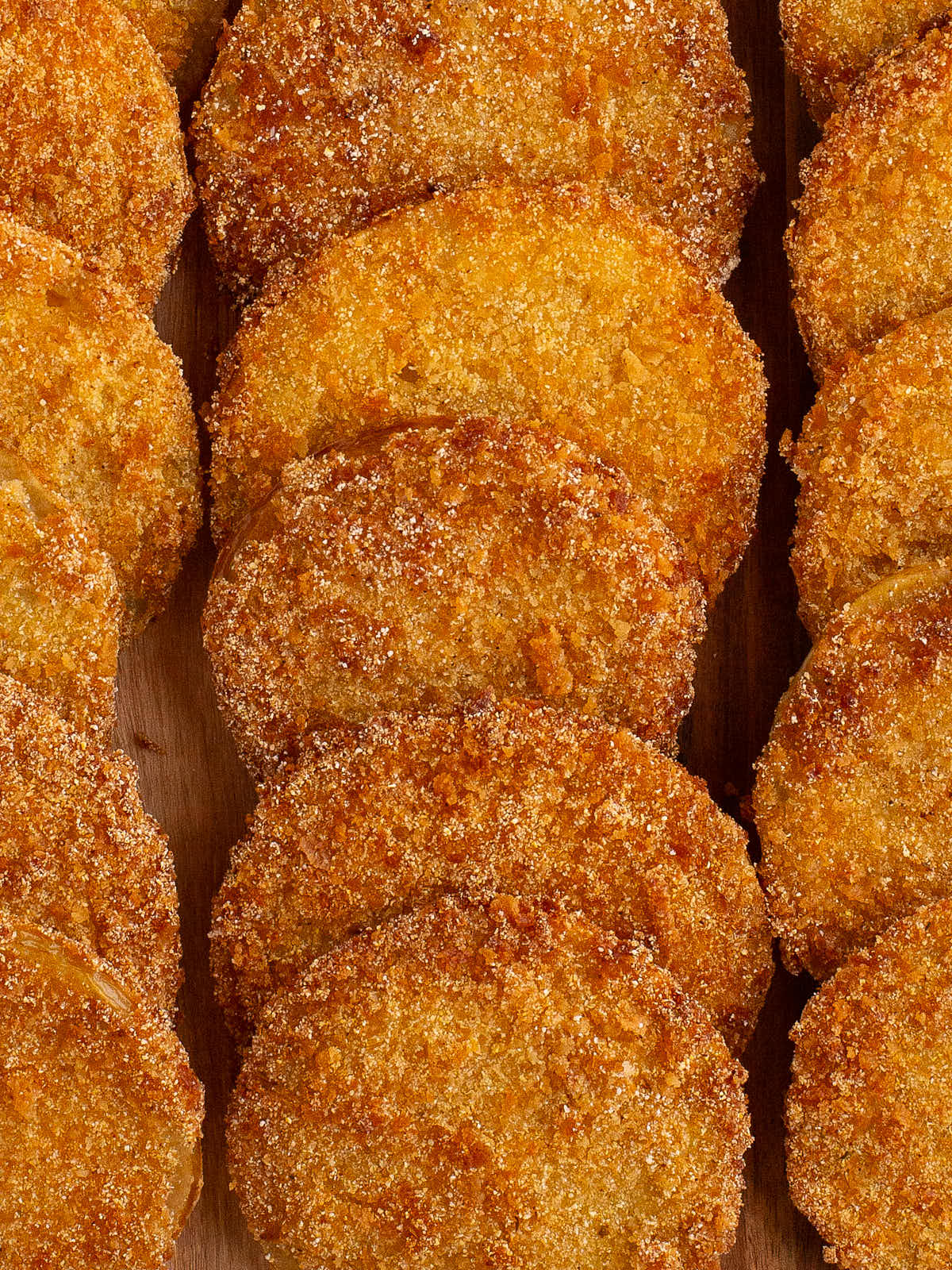 Closeup of a stack of Fried Green Tomatoes on a wooden board.