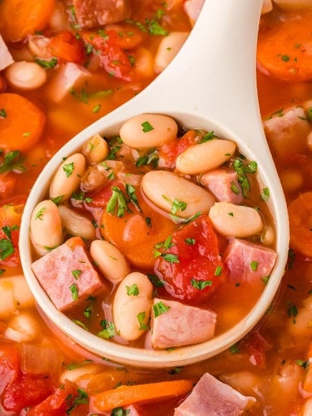 Closeup of a ladle filled with Ham and Bean Soup.