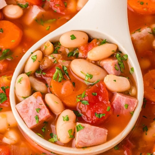 Closeup of a ladle filled with Ham and Bean Soup.