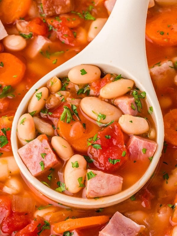Closeup of a ladle filled with Ham and Bean Soup.