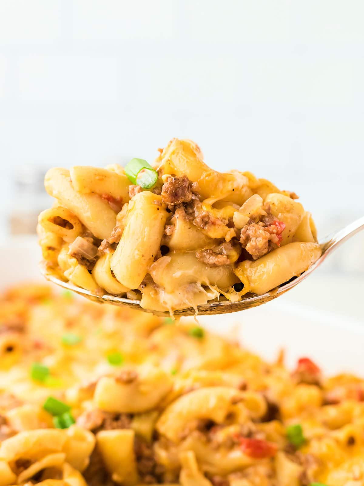 A serving spoon filled with Hamburger Casserole.
