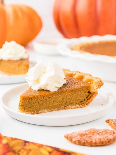 A slice of Pumpkin Pie with whipped cream on top.
