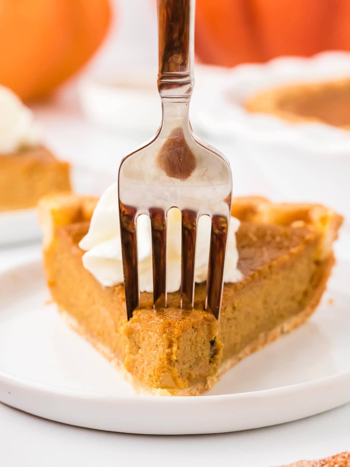 A fork digging into a slice of Pumpkin Pie.
