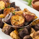 A serving spoon filled with Rosemary Roasted Potatoes.