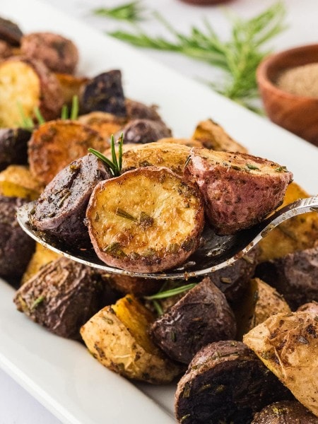 A serving spoon filled with Rosemary Roasted Potatoes.