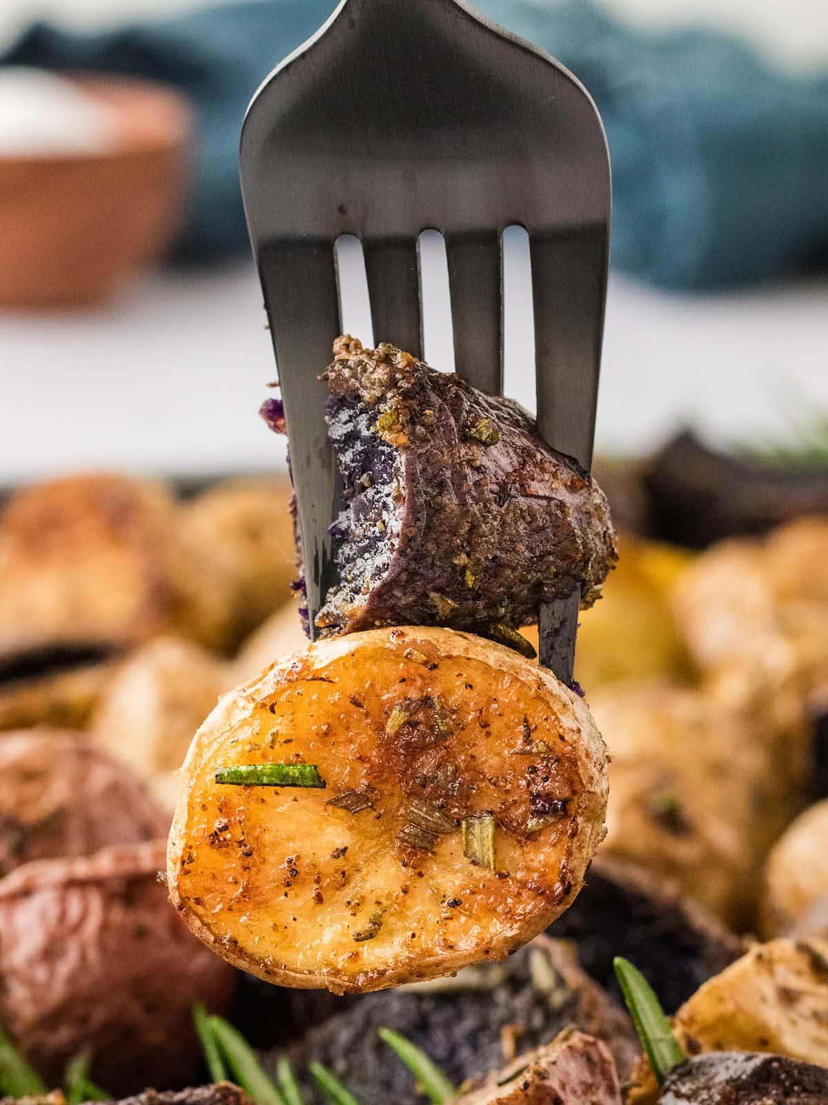 A fork with two pieces of Rosemary Roasted Potatoes.