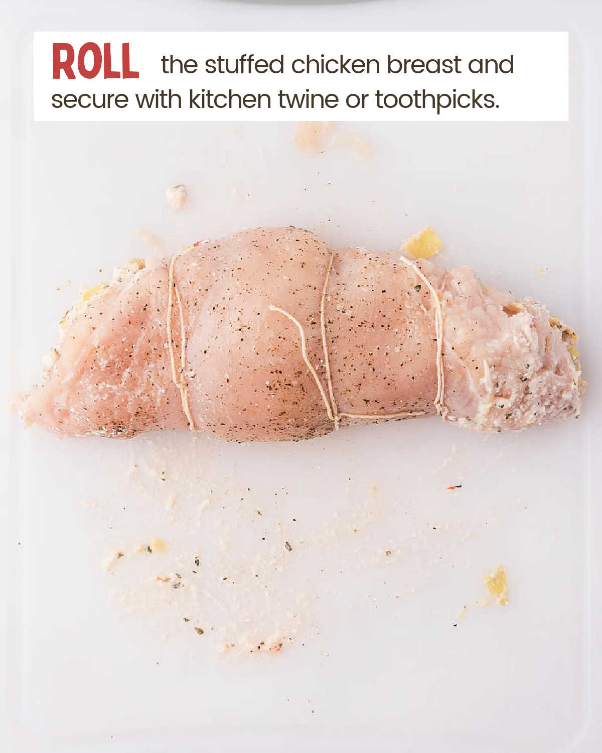 Rolling and securing the chicken breast with kitchen twine.
