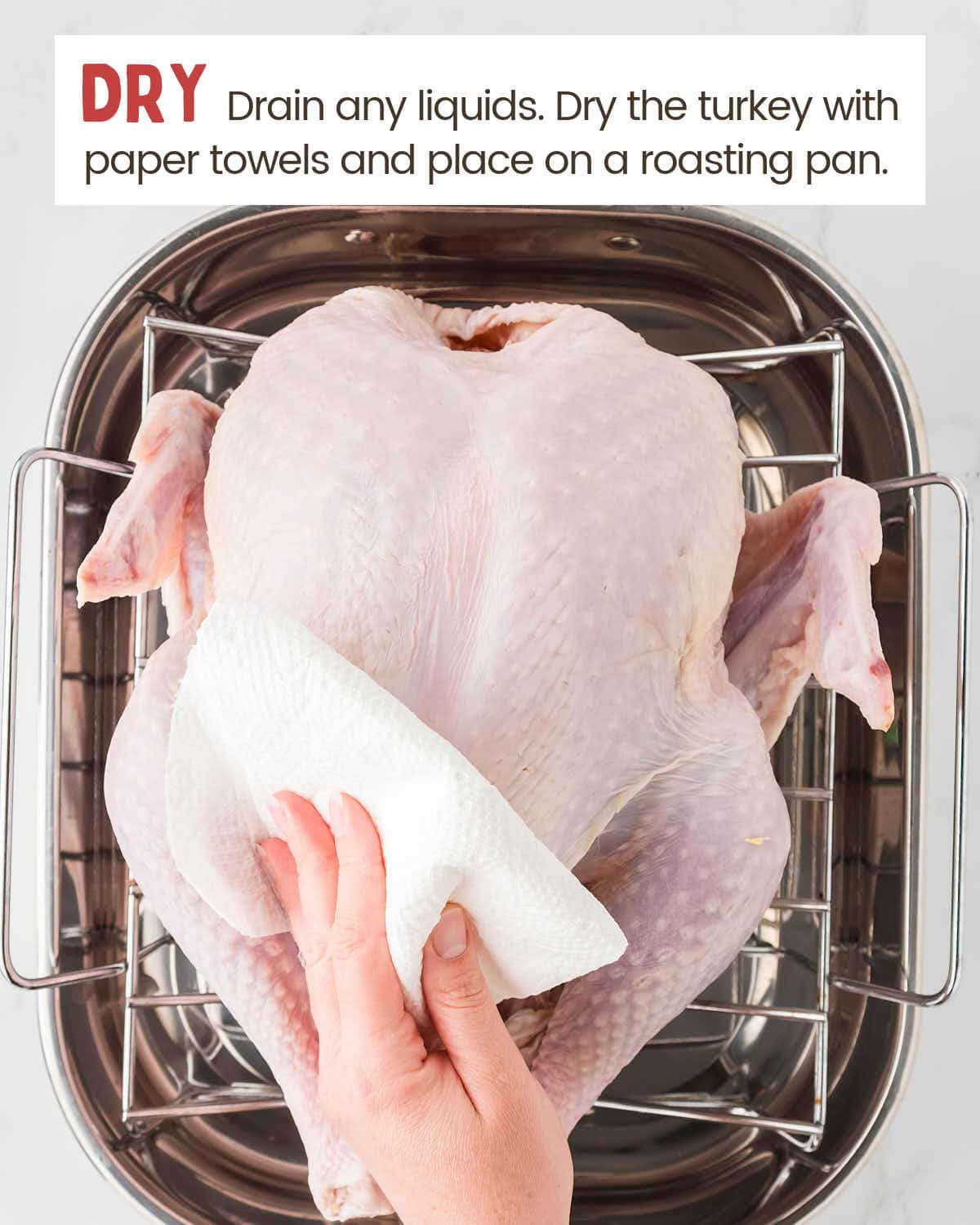 Placing the turkey on a roasting pan and patting it dry with a paper towel.