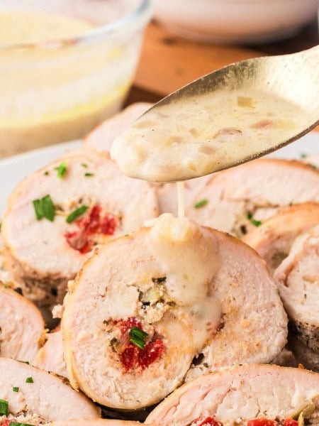 Drizzling white wine shallot sauce over sliced Chicken Rouladen.