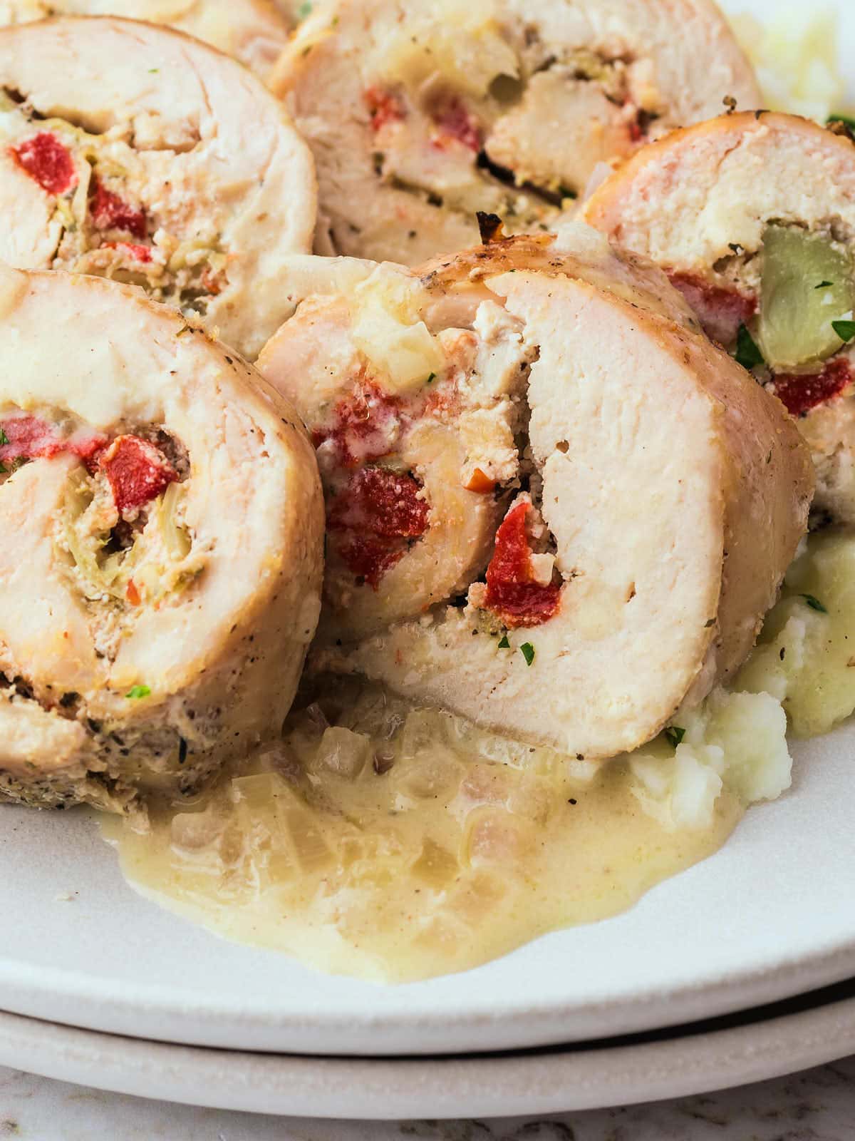 Chicken Roulades on a white plate drizzled with white wine.