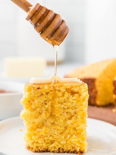 Drizzling honey over cornbread topped with a little bit of butter.