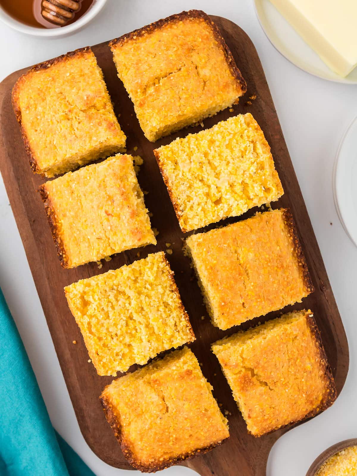 Sliced buttery Cornbread on a wooden tray.