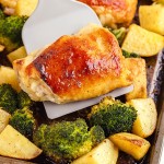 Lifting chicken thighs off a sheet pan.