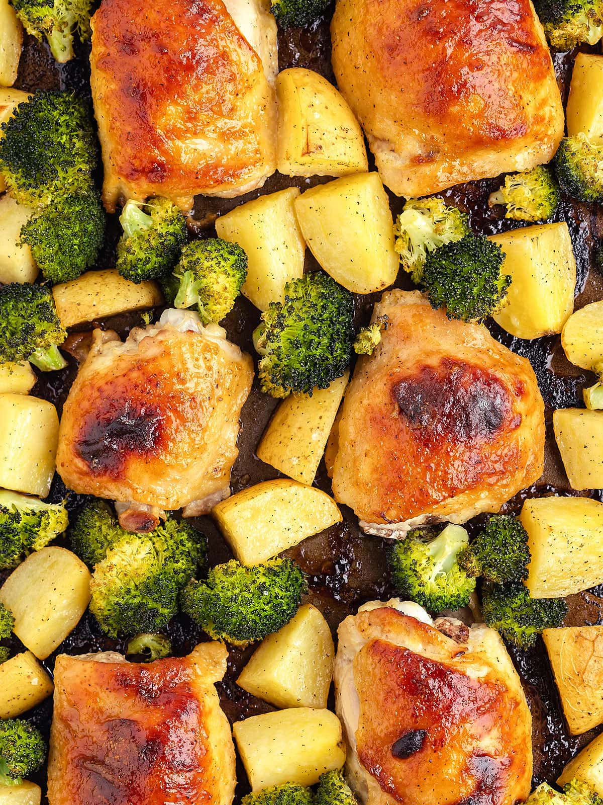 Top-down view of Chicken Thighs on a sheet pan with a broccoli and potatoes.