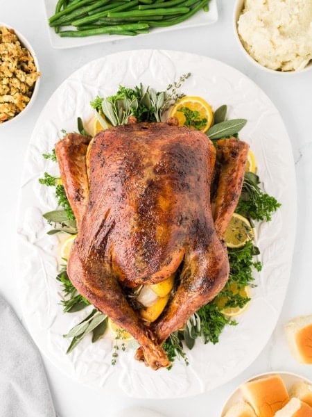 Top down view of a Thanksgiving Turkey beautifully plated on fresh herbs.