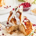 Lifting a slice of a Whole Roasted Cauliflower drizzled with Cream Sauce.