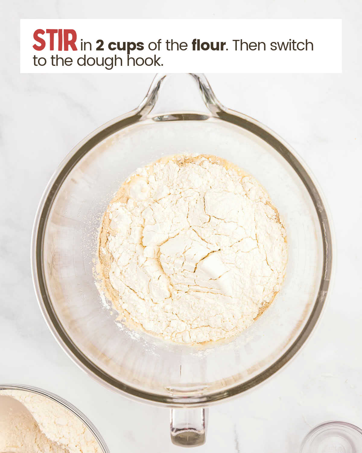 Flour covers a yeast mixture in a glass bowl.