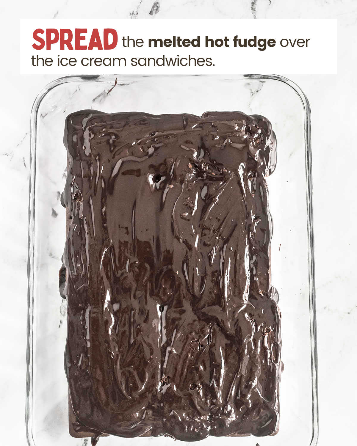 Hot fudge spread over ice cream sandwiches in a baking dish.