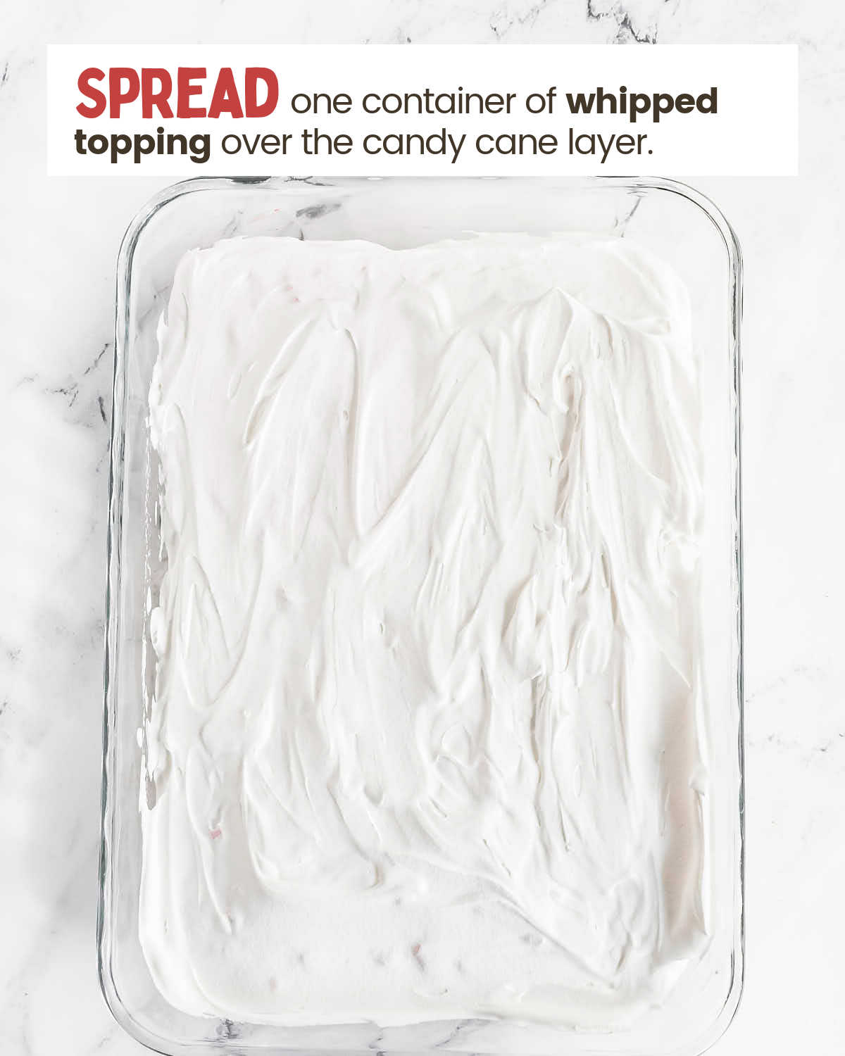 Cool whip layer of a Christmas Icebox cake in a baking dish.
