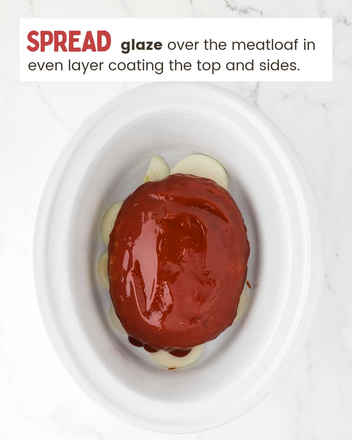 Glazed meatloaf on top of sliced onions in a slow cooker.