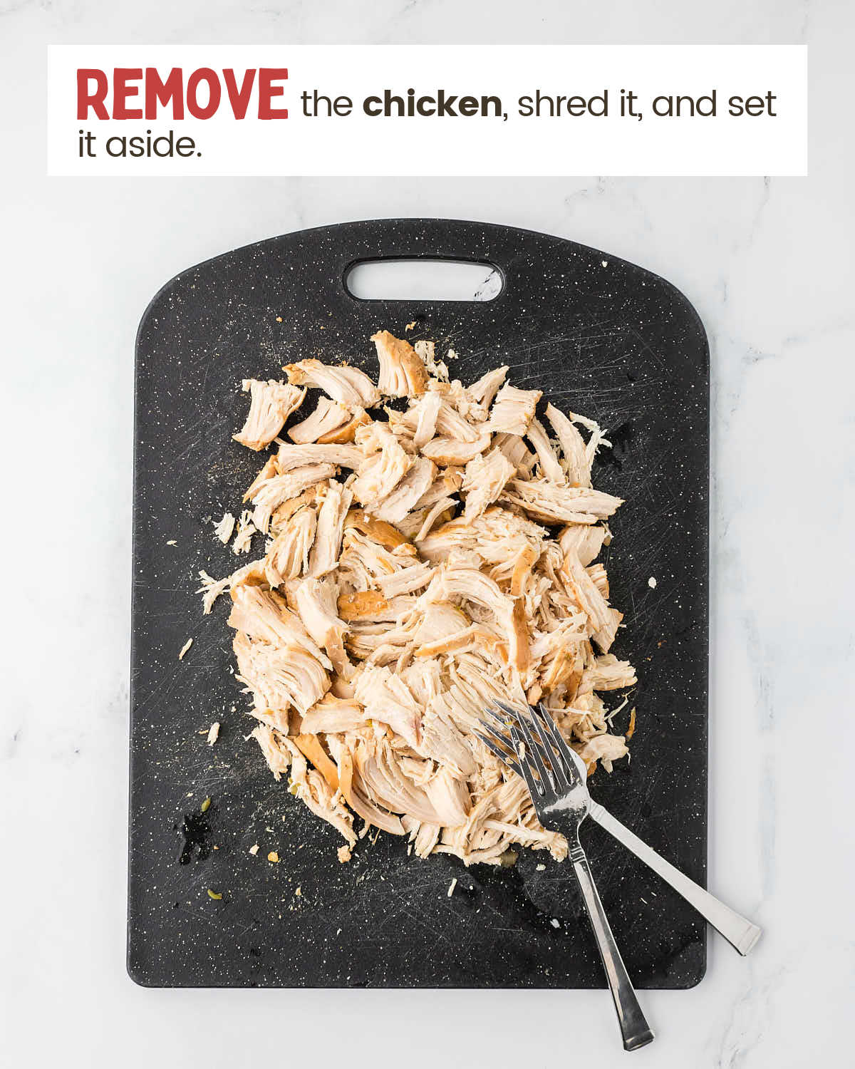 Shredded chicken on a cutting board with 2 forks. 