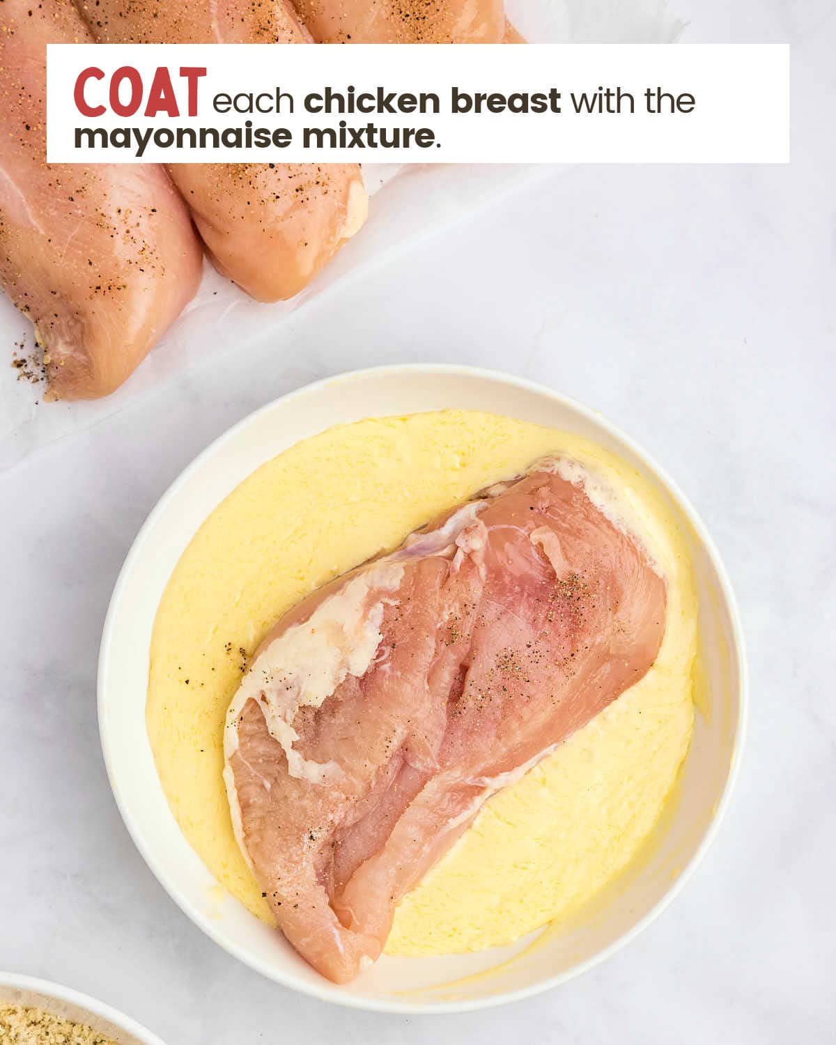 A chicken breast in a bowl with a mayo/butter mixture.
