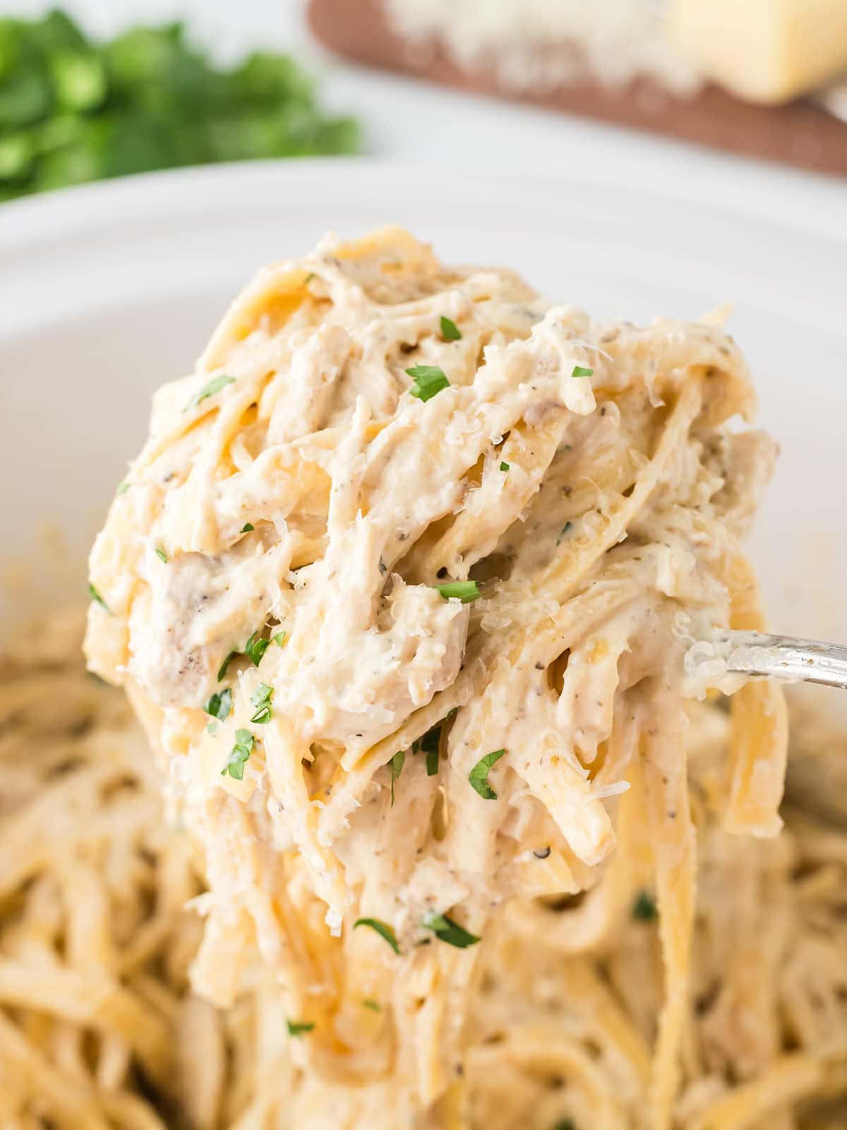 A serving spoon removing a serving of Chicken Alfredo out the Crock-Pot.