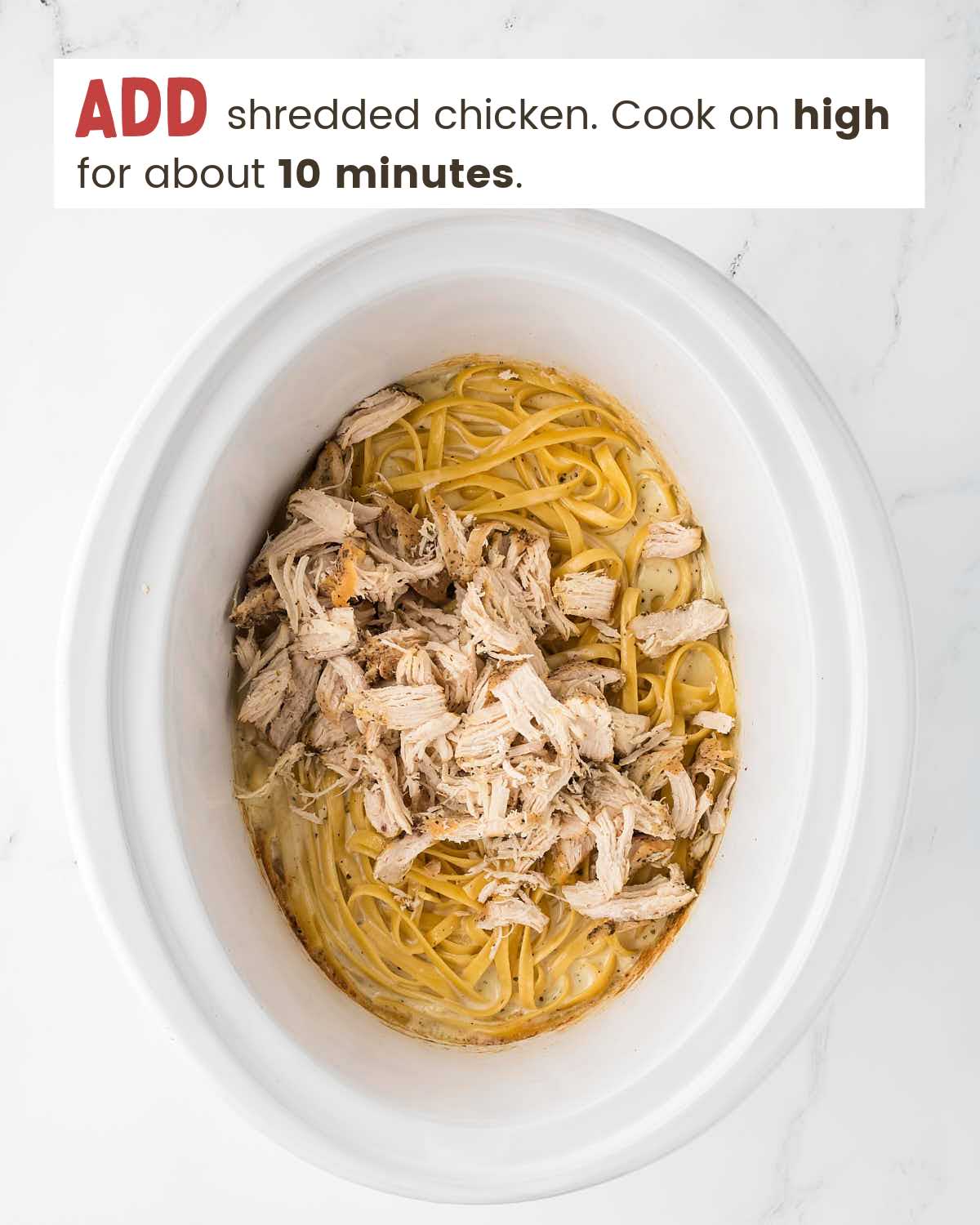 Chicken on top of alfredo noodles in a slow cooker.