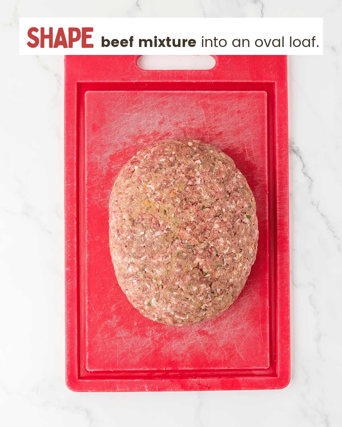 Ground beef shaped into an oval loaf on a red cutting board.