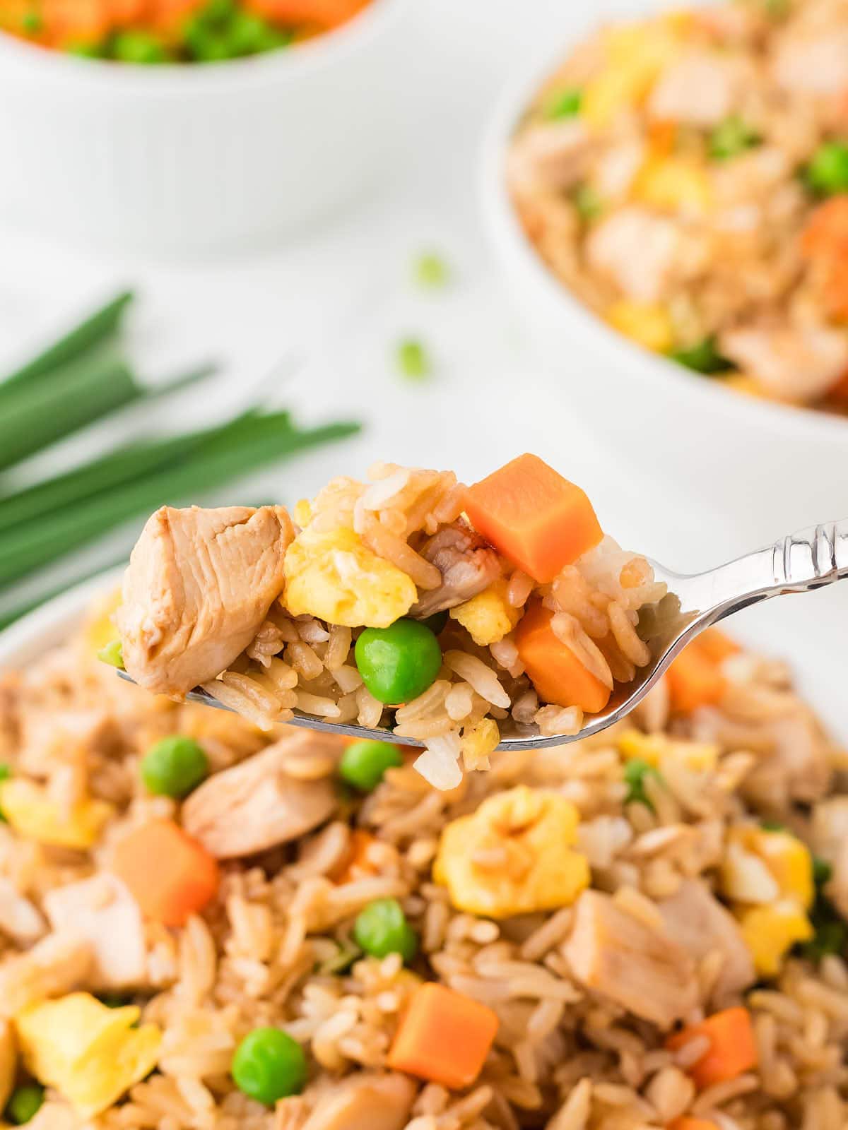 A forkful of Fried Rice in a white bowl.