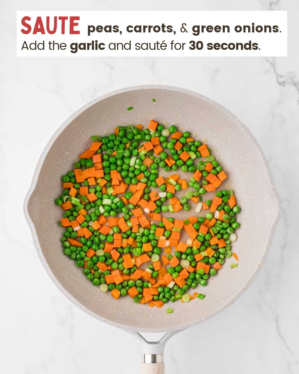 Peas, carrots, whites of green onions, and garlic in a pan.