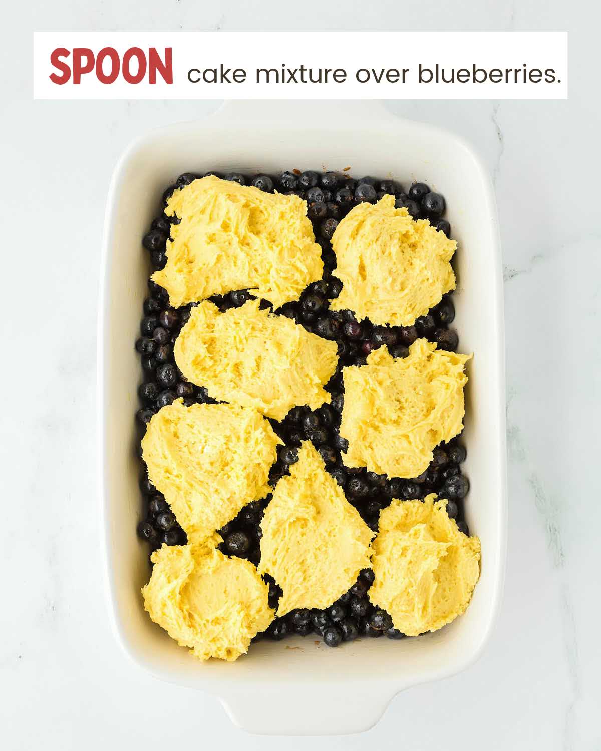 Cake batter mixture on top of blueberries in a baking dish.