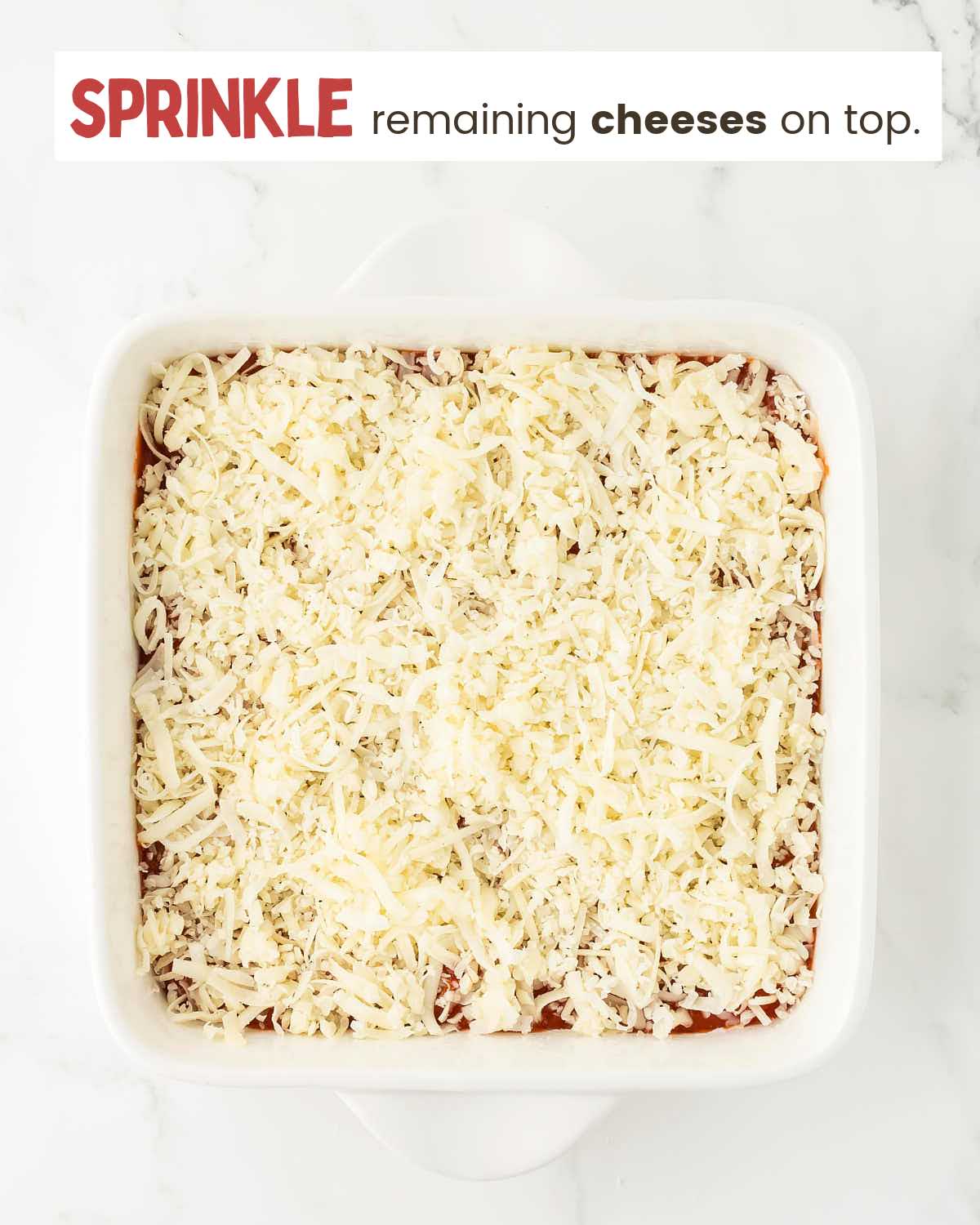 Grated cheese on top of a pizza dip in a dish.