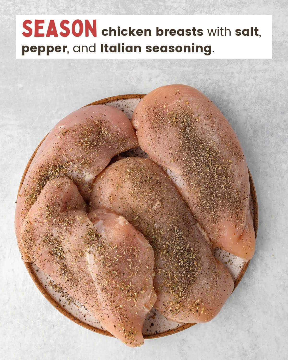 Chicken breasts seasoned with salt, pepper, and Italian seasonings on a plate.