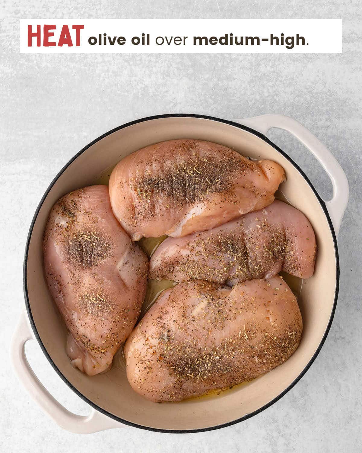 Chicken breasts seasoned with salt, pepper, and Italian seasonings in a skillet.